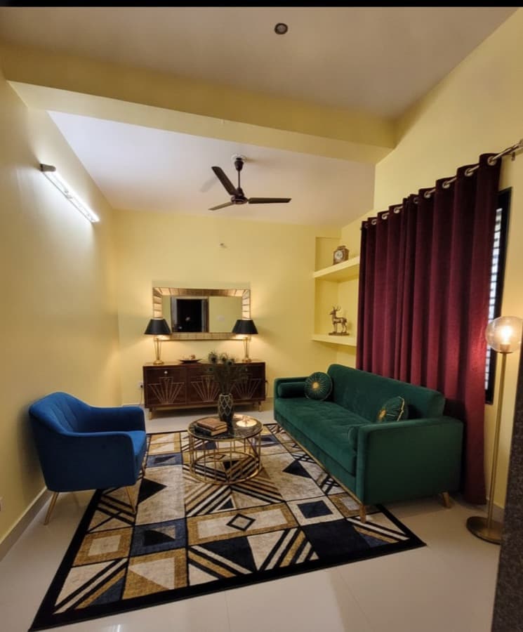 The same apartment staged in an Art Deco style with a green velvet sofa, blue armchair, geometric rug and brass lamps