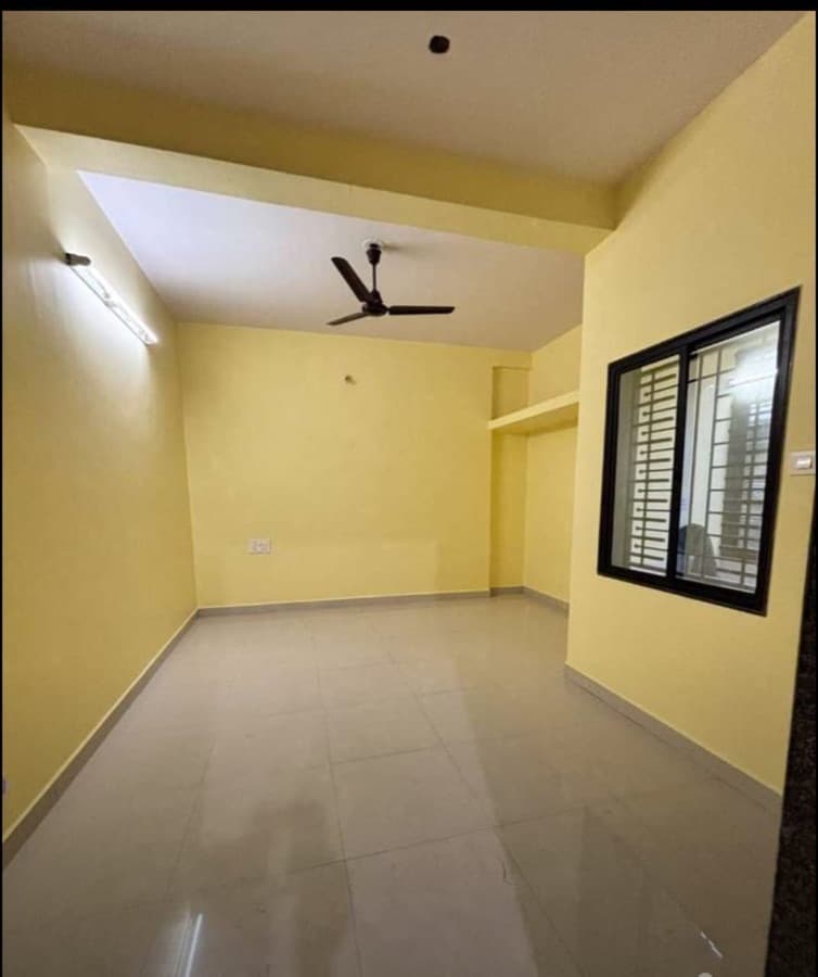 A real empty apartment photographed on a phone: yellow walls, tiled floor, ceiling fan, window