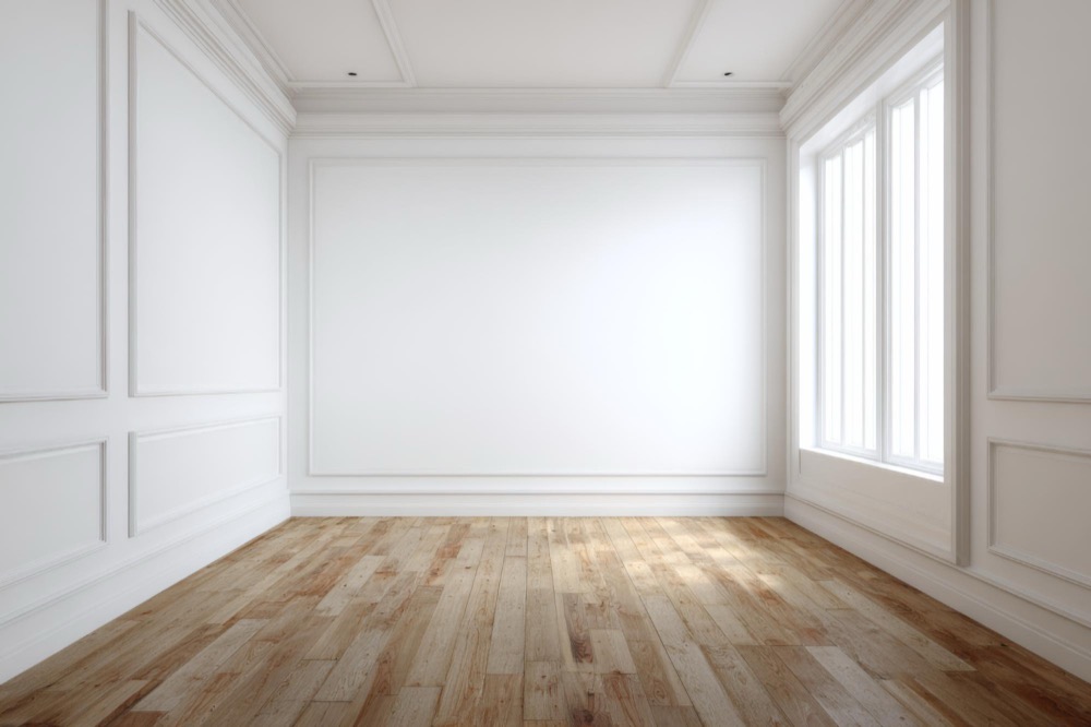 An empty living room: bare boards, panelled walls, tall windows